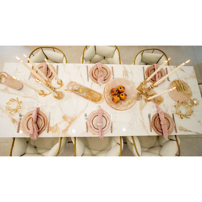 Elegant table setting with marble tablecloth, gold cutlery, and pink napkins.